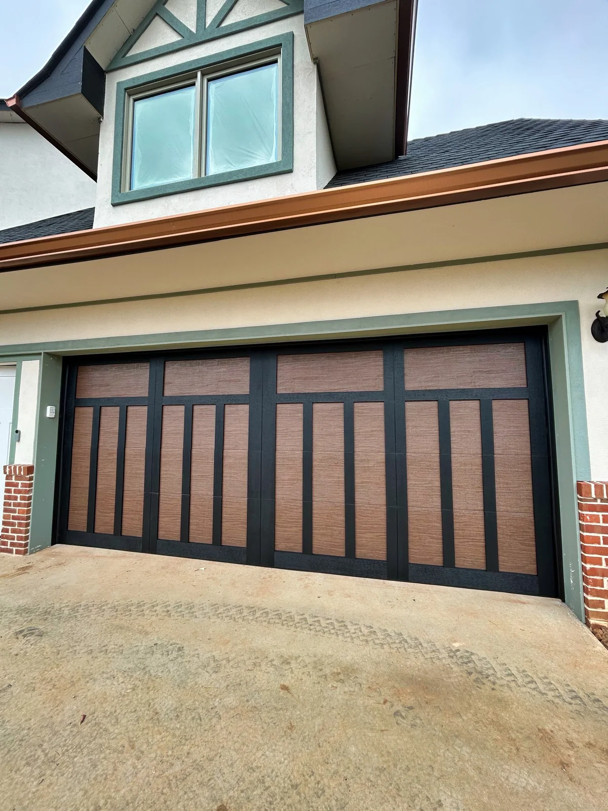 Completed wood-look carriage-style garage door on a brick and siding home