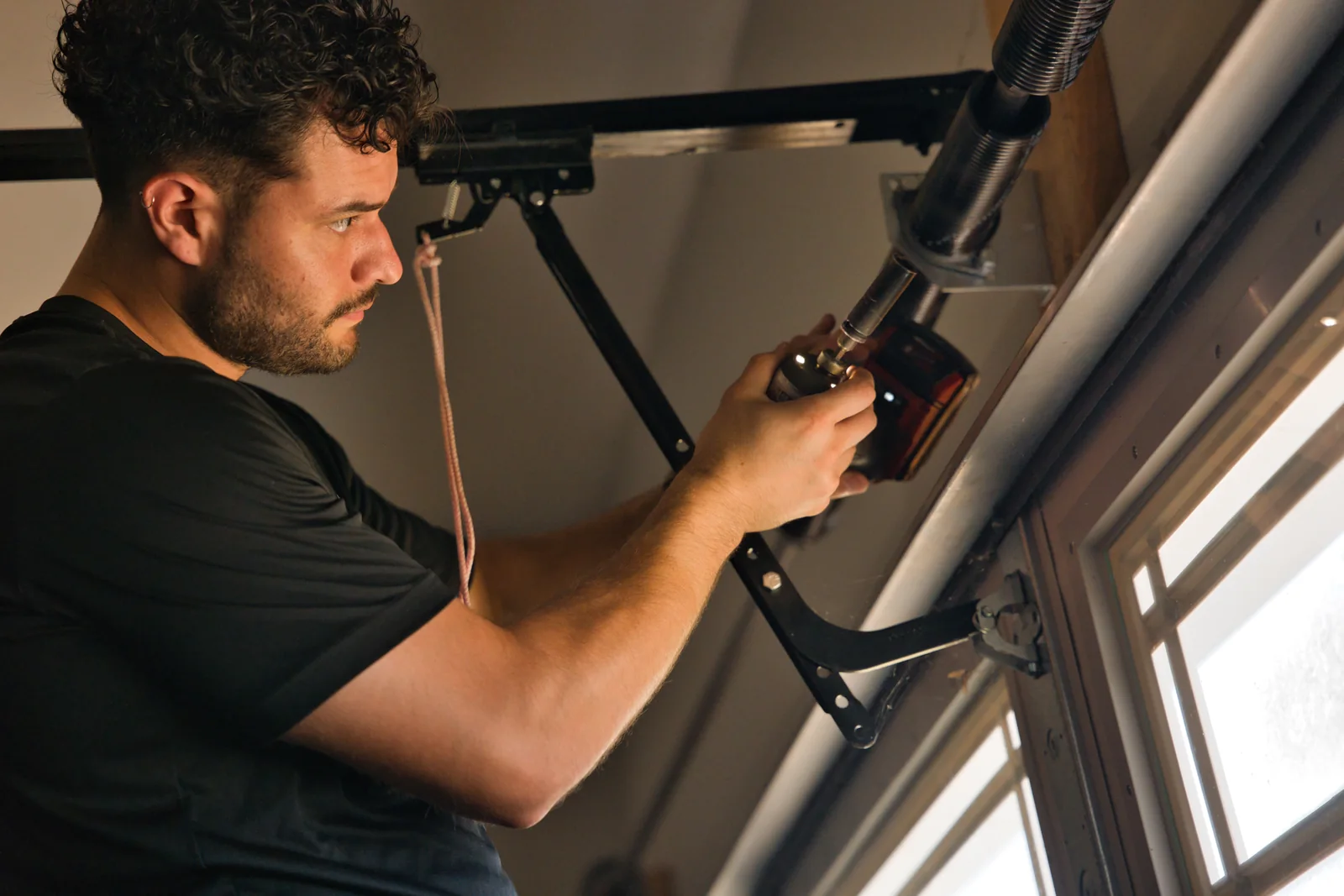 Blue Jay technician working on spring hardware above a garage door